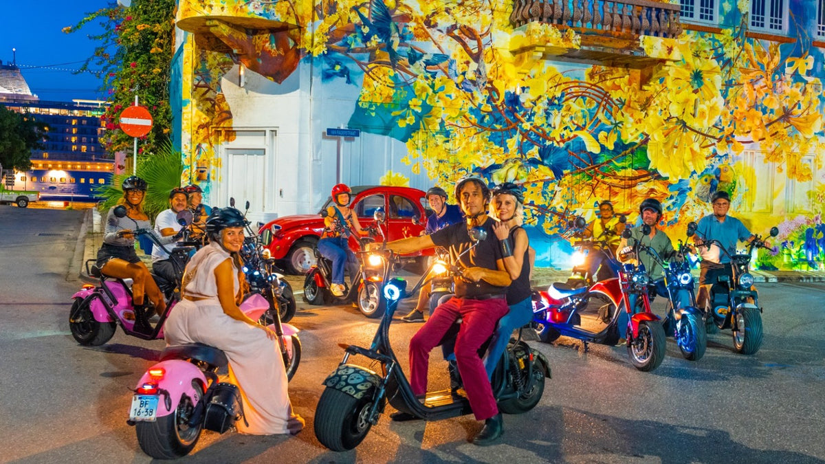 Iguana Ride Curaçao evening scooter tour in front of a colorful Willemstad mural
