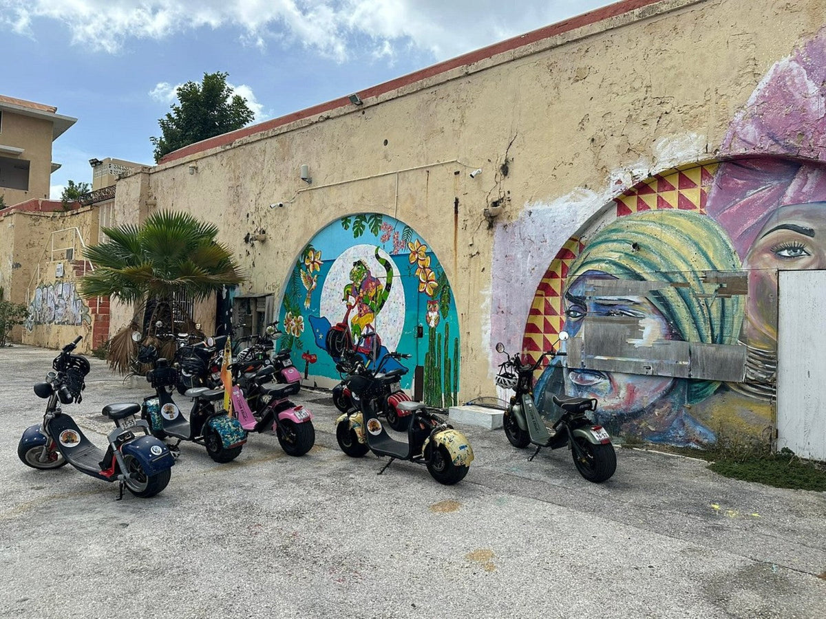 Iguana Ride electric scooters by colorful murals in Willemstad, Curaçao